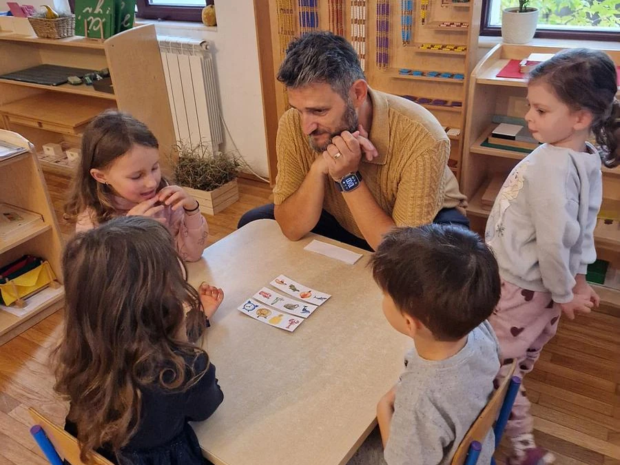 Profesor și copii lucrând împreună la activitatea de engleză Arcadia Montessori
