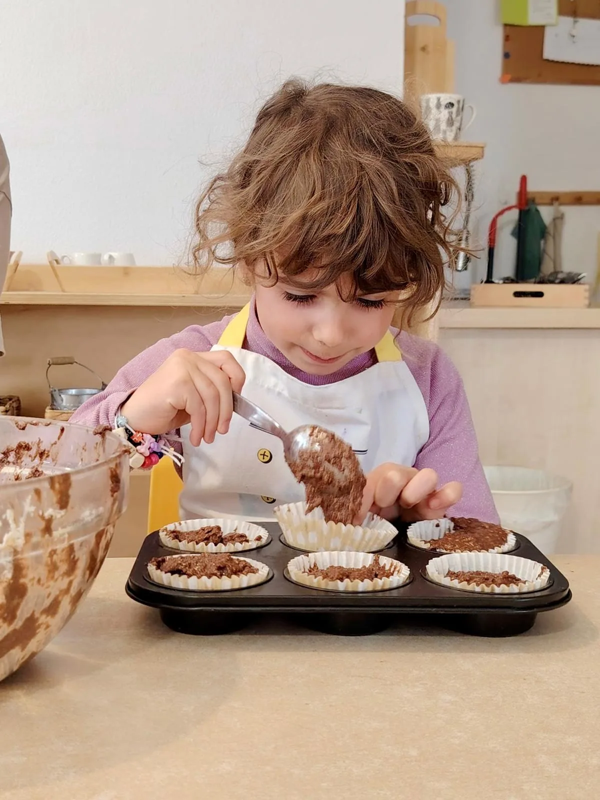 Copil umplând forme de brioșe la atelierul de gătit, Arcadia Montessori
