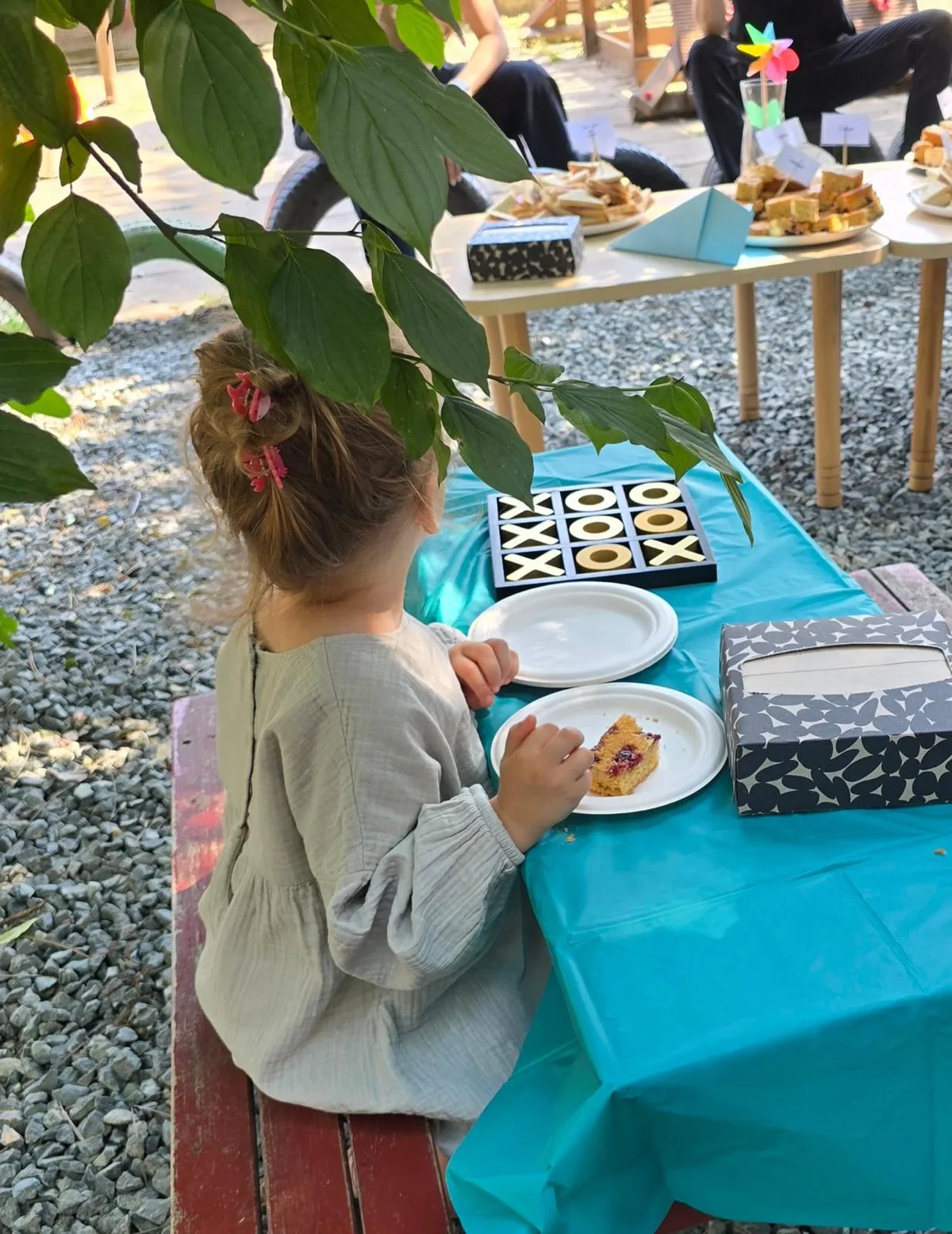 Copil așezat la o masă cu joc X și 0 din lemn, la evenimentul de sfârșit de an școlar 2025–2026, Arcadia Montessori