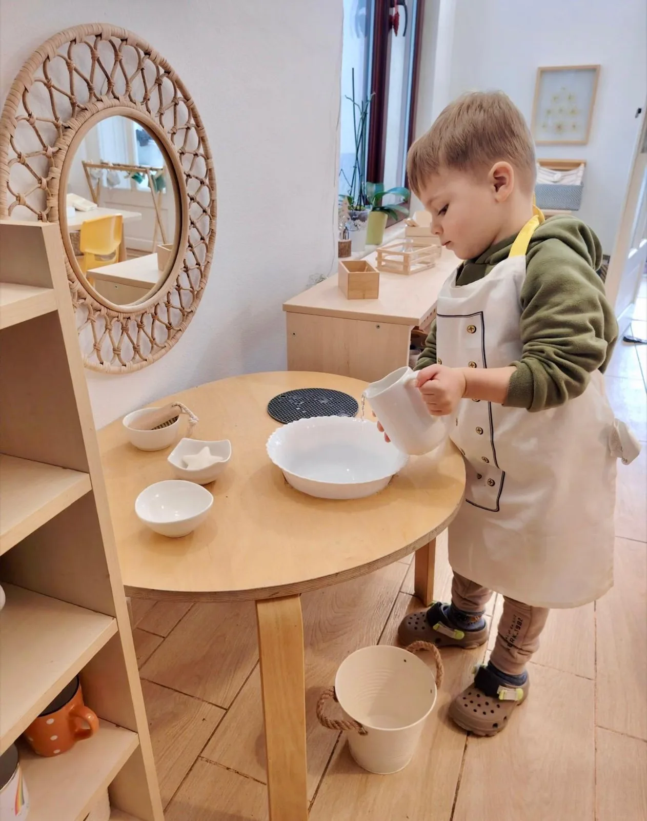 Copil turnând apă dintr-o cană, activitate de viață practică la Arcadia Montessori