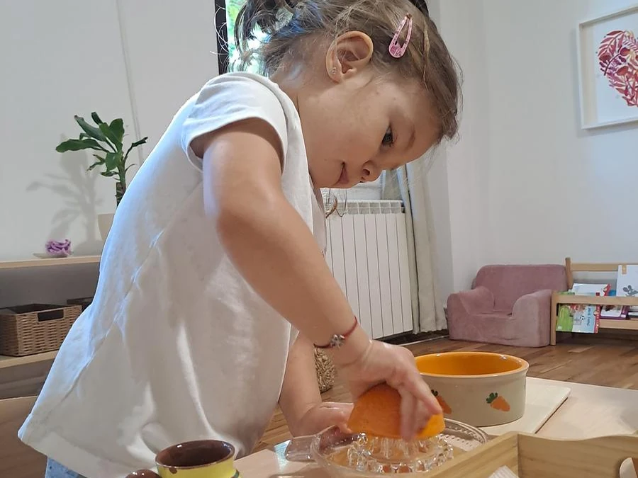Copil pregătind suc de portocale în Grupa 1,8-3 ani de la Arcadia Montessori