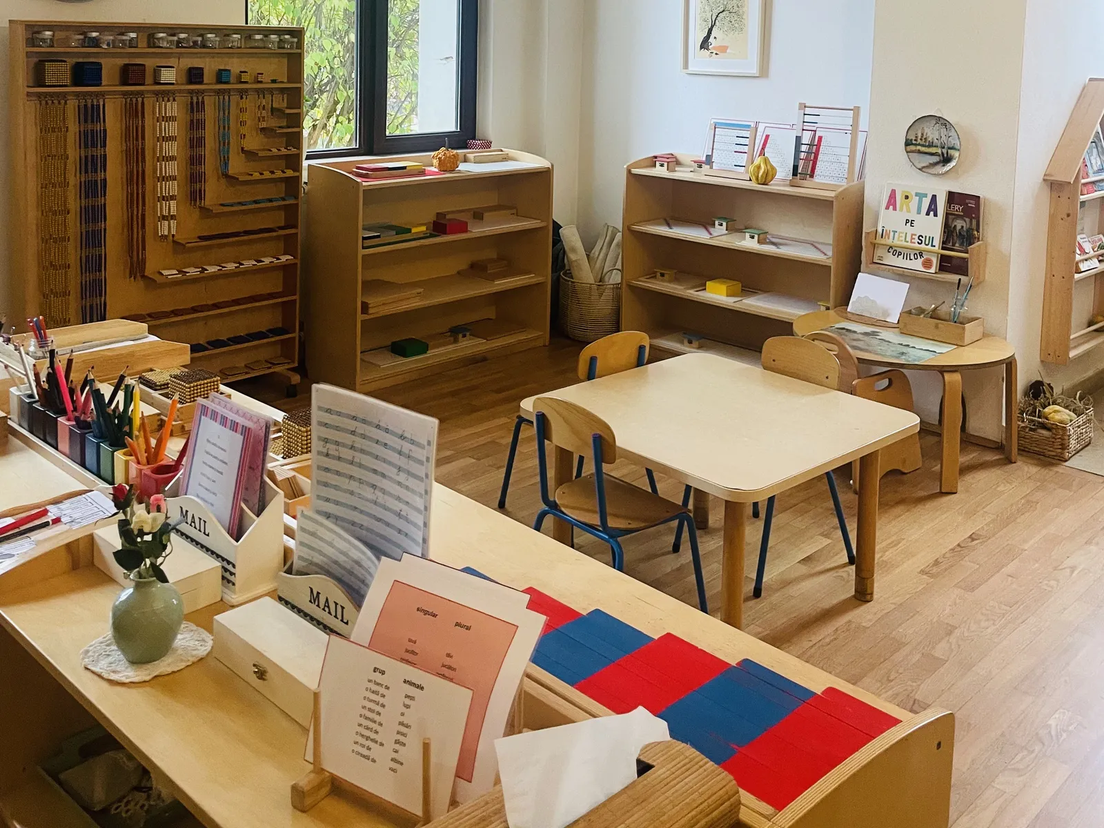 Clasă Montessori pregătită, cu măsuțe pentru copii și materiale pe rafturi joase, Arcadia Montessori
