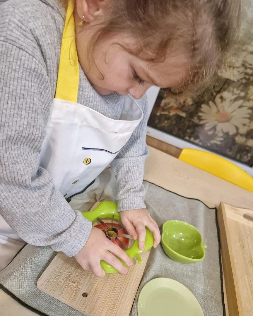 Copil pregătind alimente la masa de viață practică, Grupa 3-6 ani, Arcadia Montessori
