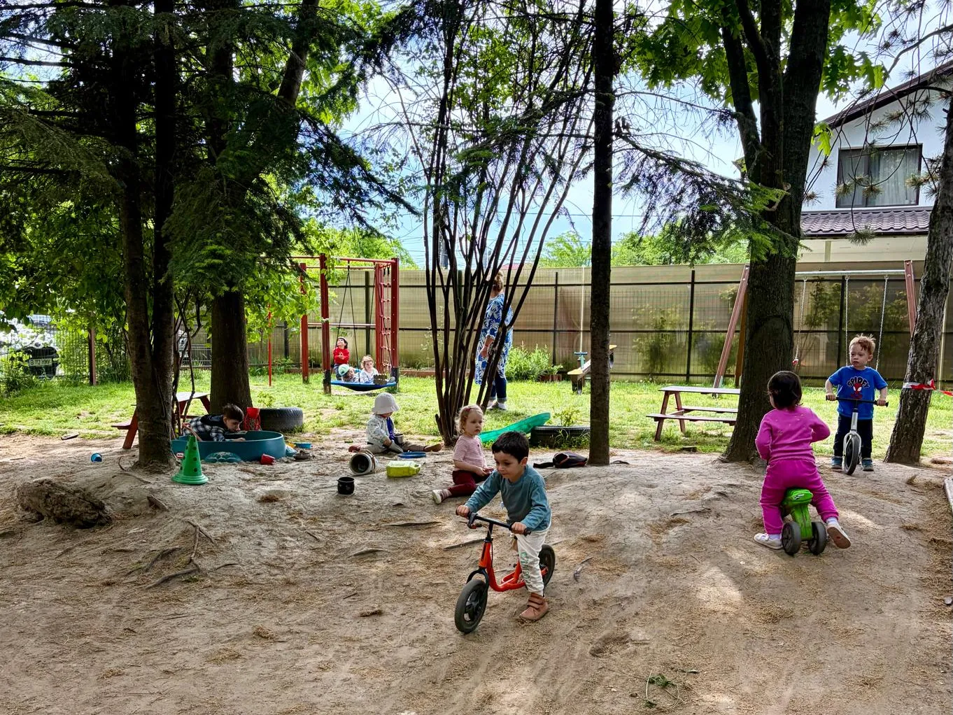 Copii pe biciclete fără pedale și la joacă în grădina de 1.000 mp a Arcadia Montessori