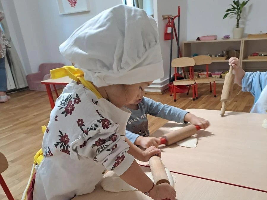 Copil lucrând aluatul la atelierul de gătit, în Grupa 1,8-3 ani de la Arcadia Montessori