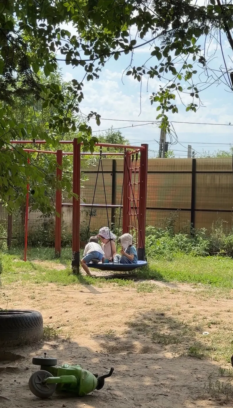 Copii în leagănul cuib din grădina Arcadia Montessori