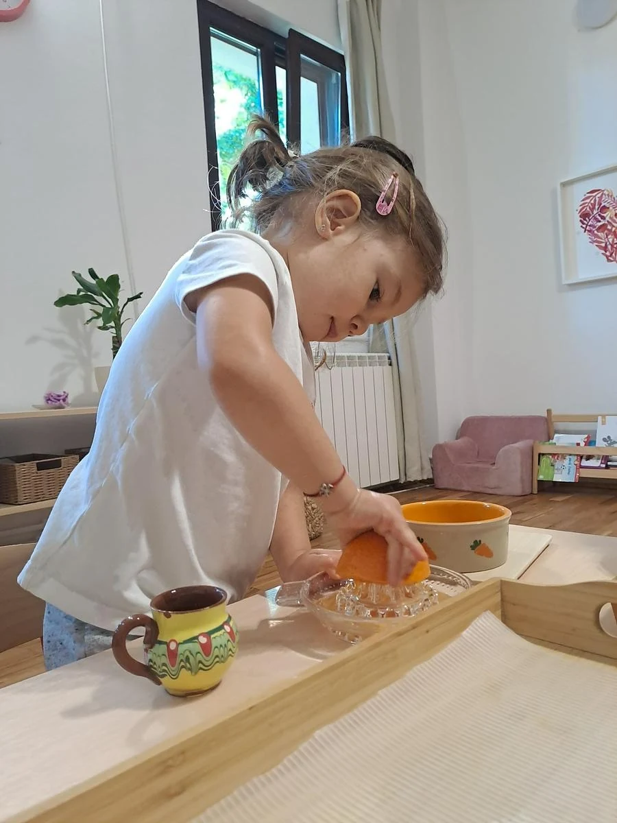 Copil pregătind suc de portocale în activitatea de viață practică, Grupa 3-6 ani, Arcadia Montessori