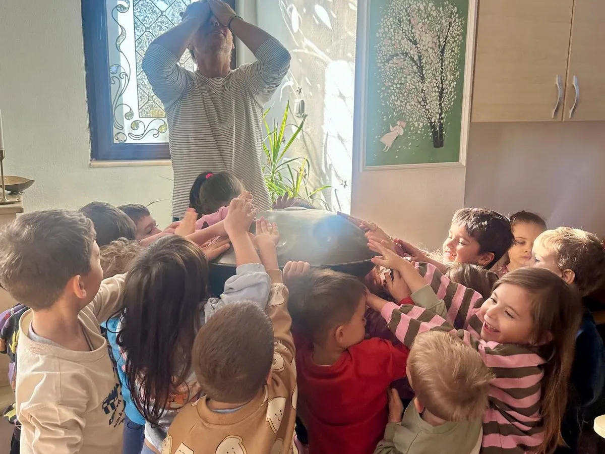 Copii la un atelier de muzică, atingând un instrument handpan, la Arcadia Montessori