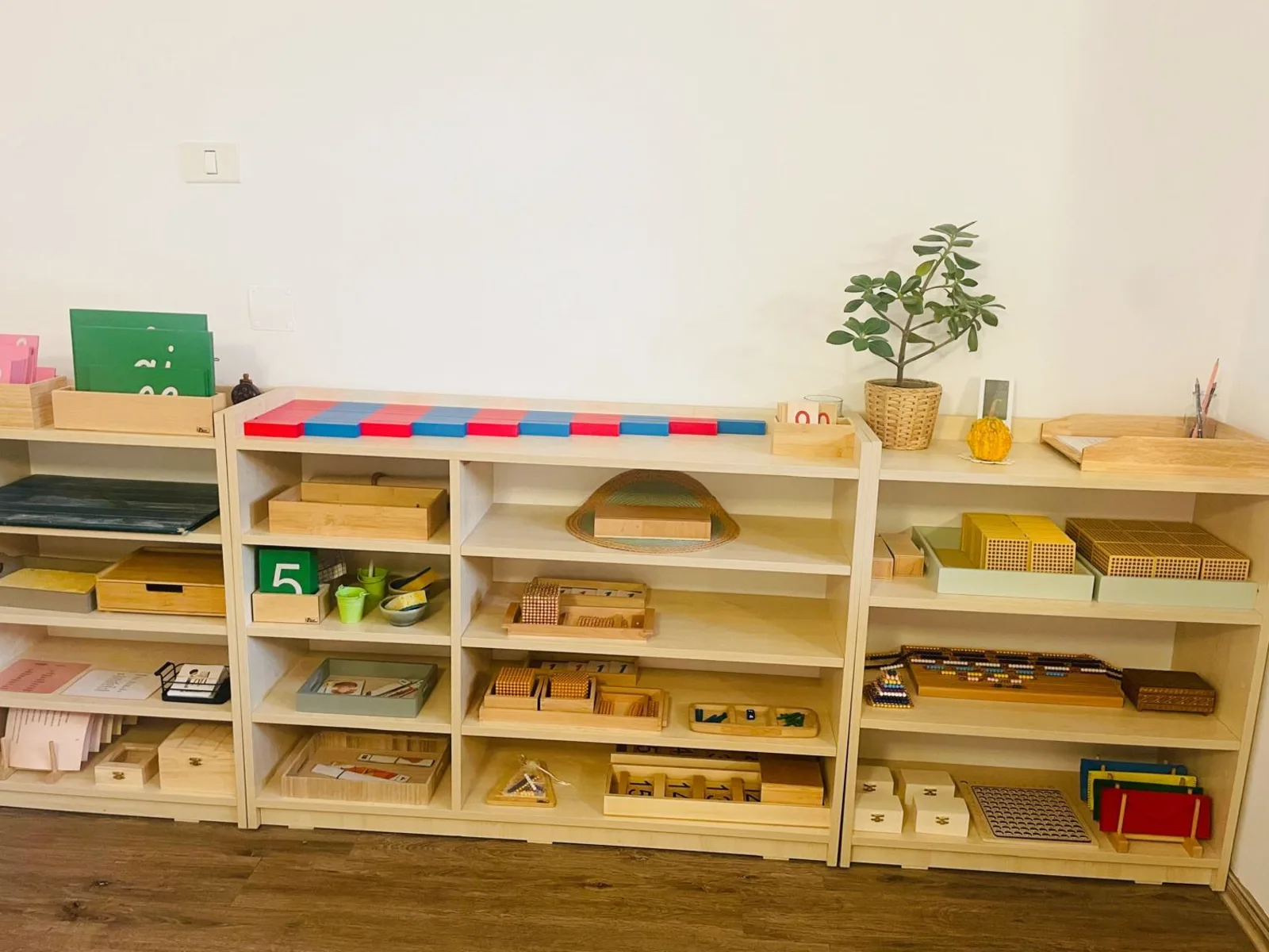 Rafturi cu materiale Montessori colorate, în clasa Arcadia Montessori Corbeanca