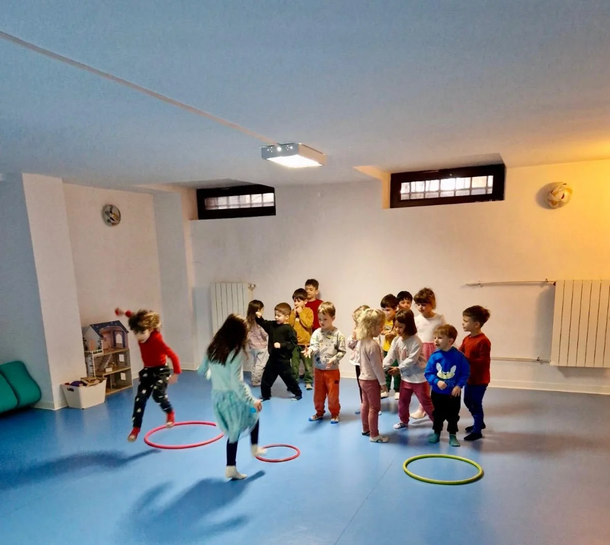 Copii la activitate de mișcare cu cercuri, în sala de sport Arcadia Montessori