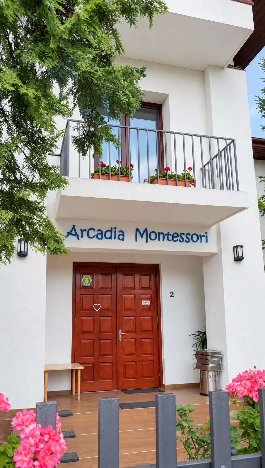 Intrarea în clădirea Arcadia Montessori din Corbeanca, cu flori și verdeață